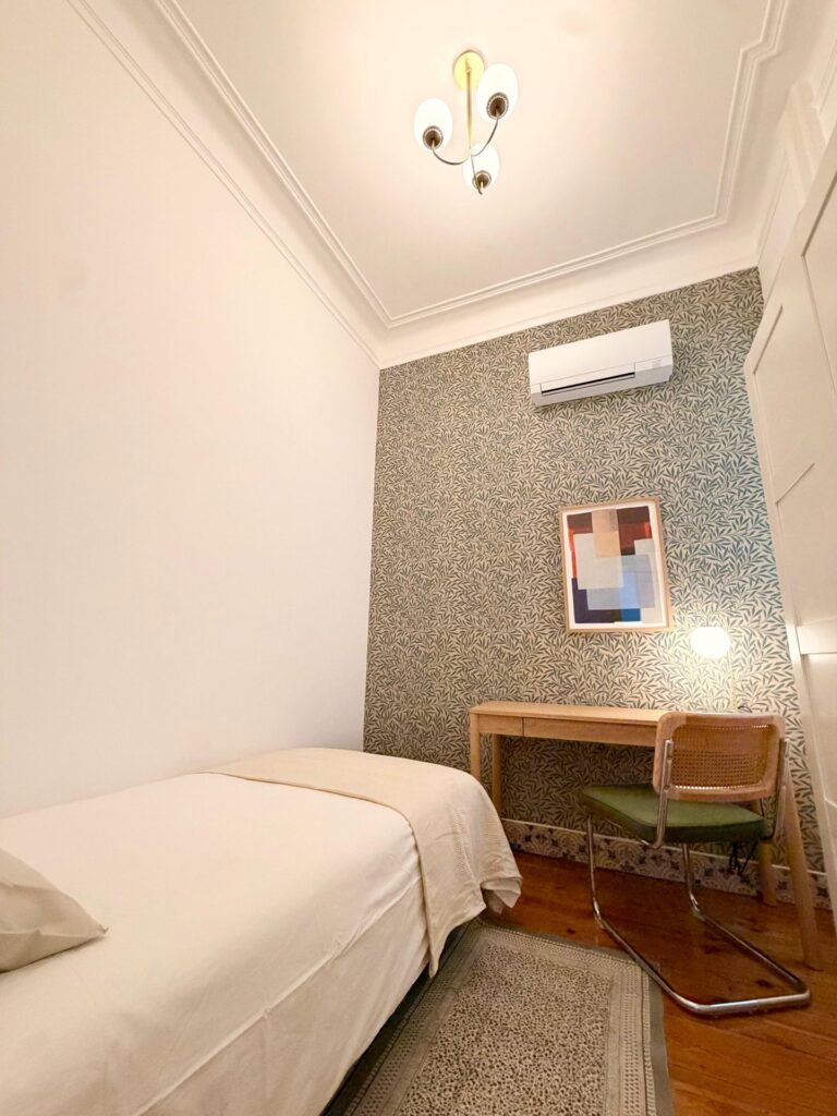 Single room with desk, cane chair and air conditioning at LX1 Coliving