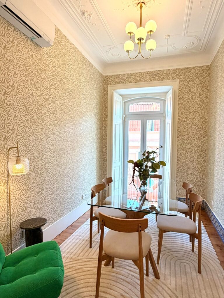 Shared dining room with glass table and ornate ceiling at LX1 Coliving